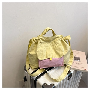 Détail d'un sac fourre-tout en nylon jaune et rose sur une valise blanche, style décontracté