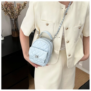 Close-up of light blue quilted mini crossbody bag with silver chain and metal turn-lock