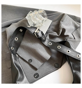 Detail of black glossy leather hobo bag featuring wide metallic eyelet strap and soft texture