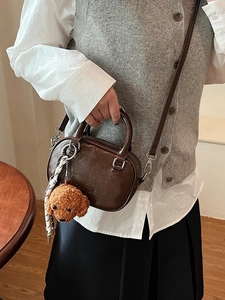 Vintage brown oil-wax leather handbag with plush dog pendant worn by a model
