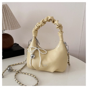 Detail of ruched handbag handle with pearl bow and heart charm on yellow bag