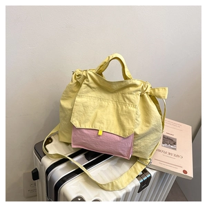 Détail du sac cabas en nylon jaune avec poche plissée rose sur bagage rayé