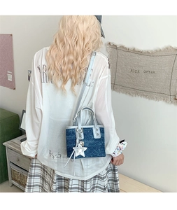 Denim bucket bag with silver trim and star charm shown in a minimalist lifestyle setting