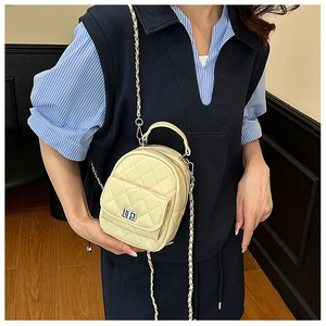 Detail of a quilted cream mini backpack with chain strap and twist lock closure