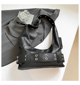 Detail of black leather underarm bag featuring silver metal eyelets and moto style