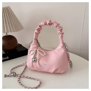 Detailed shot of pink pleated handbag with pearl butterfly charm and fashion text