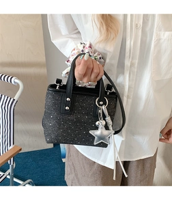 Detail of a mini black sequined bucket bag with a silver star charm and crossbody strap