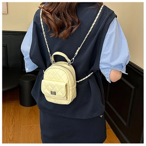 Detail of light yellow quilted mini backpack with metal chain strap and silver buckle