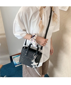 Detail of mini black sequined bucket bag with silver star charm and chain strap