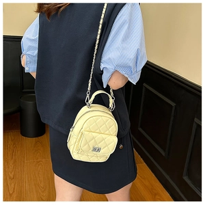 Detail of yellow quilted mini bag with silver twist lock and metal chain strap