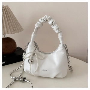 Detail view of white ruched crossbody bag with pearl bow and heart charm accents