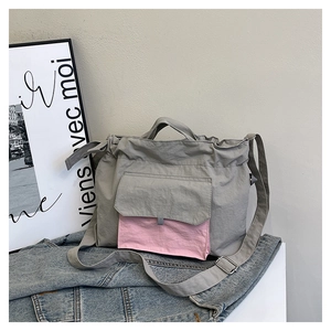 Détail du fourre-tout en nylon gris avec rabat rose contrasté et poignée