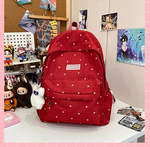 Detail of red floral canvas backpack with white flower pattern and plush bunny pendant
