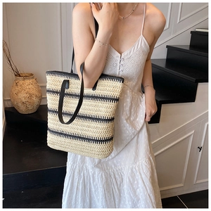 Détail d'un sac cabas en paille tissée à rayures noires et blanches et anses en cuir