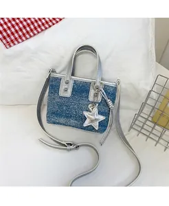 Detail of blue denim mini tote bag with silver leather straps and a glitter star charm