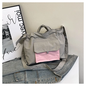 Détail du sac fourre-tout en nylon gris avec poche rose sur fond de denim décontracté