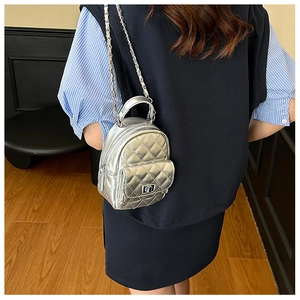 Detail view of mini silver quilted chain bag with metallic finish worn as a crossbody