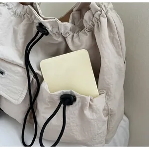 Detail der beigen Nylon-Umhängetasche mit funktioneller vorderer Kordelzugtasche