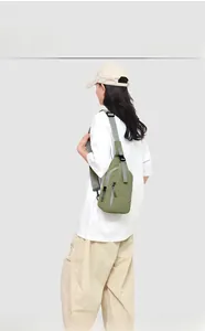Vue détaillée du sac bandoulière en nylon vert herbe porté sur un t-shirt blanc ample