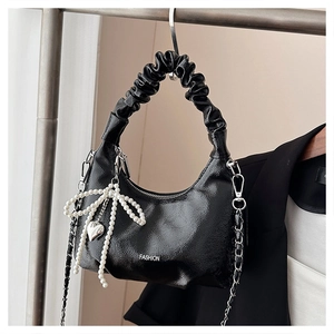 Detail view of the black pleated handle bag with a pearl bow and heart charm