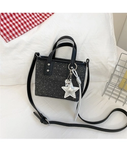 Detail of black denim bucket bag with white polka dots and silver star charm