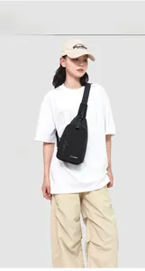 Gros plan sur le sac bandoulière noir en nylon avec poche zippée porté par un homme