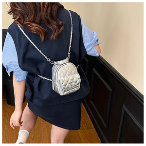 Silver mini quilted backpack with chain strap shown on model to display compact size