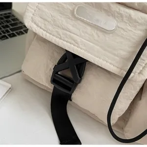 Nahaufnahme der schwarzen Schnalle und der beigen Nylon-Kordeltasche mit Markenetikett