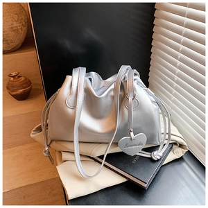 Detail of silver pleated bucket bag with drawstring closure and heart charm accessory