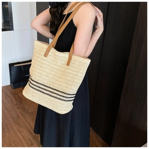 Détail du sac cabas en paille tressée avec rayures noires et anses en cuir marron