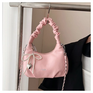 Detail of pink pleated handbag with pearl bow charm and silver chain strap hanging on hanger