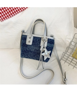 Detail of navy denim bucket bag with white polka dots and silver star charm pendant