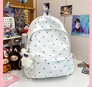 Close-up of white floral backpack with black polka dots and cute plush rabbit charm
