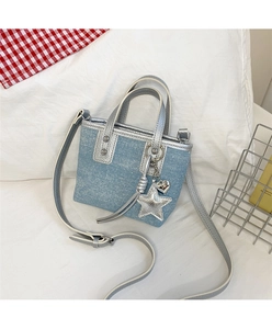 Detail of light blue denim mini bucket bag with silver leather trim and metal charms