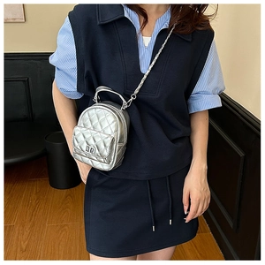 Close-up of silver quilted mini backpack with metal chain strap and turn-lock closure
