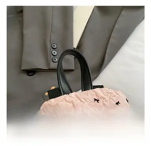 Detail eines rosa Rucksacks mit schwarzem Ledergriff und goldenem Reißverschluss