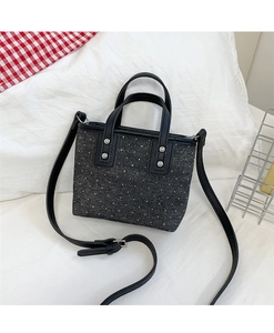 Detailed shot of dark grey polka dot canvas bucket bag with black leather handles
