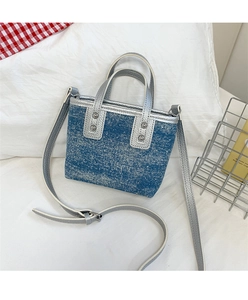 Detail of blue denim bucket bag with silver metallic trim and riveted handles