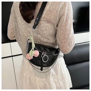 Detail of black semi-circular saddle bag featuring silver chain and woven charm pendant