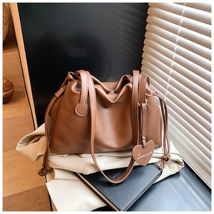 Detailed view of caramel leather shoulder bag with side drawstring and heart charm