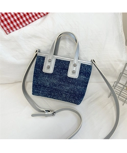 Detail of mini denim bucket bag with white dots, silver studs and adjustable strap
