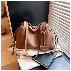 Detail of dark brown leather bucket bag with heart pendant and drawstring design