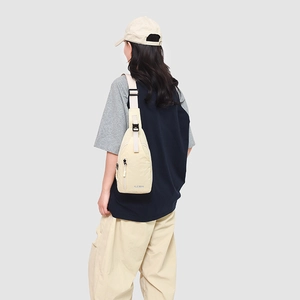 Détail d'un sac de poitrine beige léger avec bandoulière ajustable porté par un mannequin