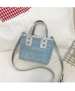 Close-up of light blue denim bucket bag with metallic silver leather trim and rivets