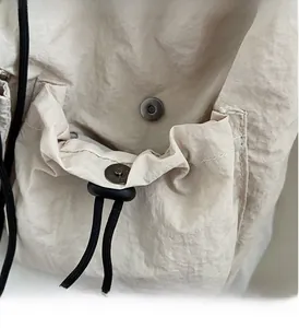Detail der matten Magnetschnalle und des Kordelzugs an der cremefarbenen Nylontasche