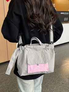 Sac fourre-tout chic en nylon gris avec poche rose porté par un mannequin au style urbain