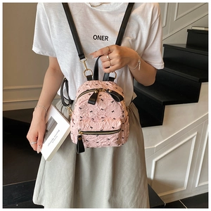 Detail eines rosa Mini-Rucksacks mit Schleifendruck und Strukturstoff am Modell