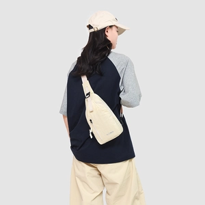 Détail du sac bandoulière en nylon beige avec logo KLEIMAN et poche zippée pratique
