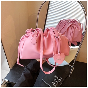 Close-up of pink bucket bag with drawstring closure and a heart-shaped charm detail