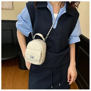 Detail of beige quilted PU leather backpack with silver turn-lock and chain strap